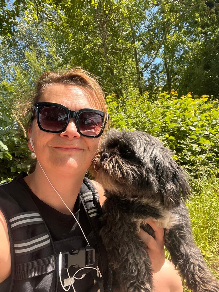 smiling woman with auburn hair, called Tabitha Wright, sitting outside in the countryside with her dog, founder and owner of Shine at The Hollies