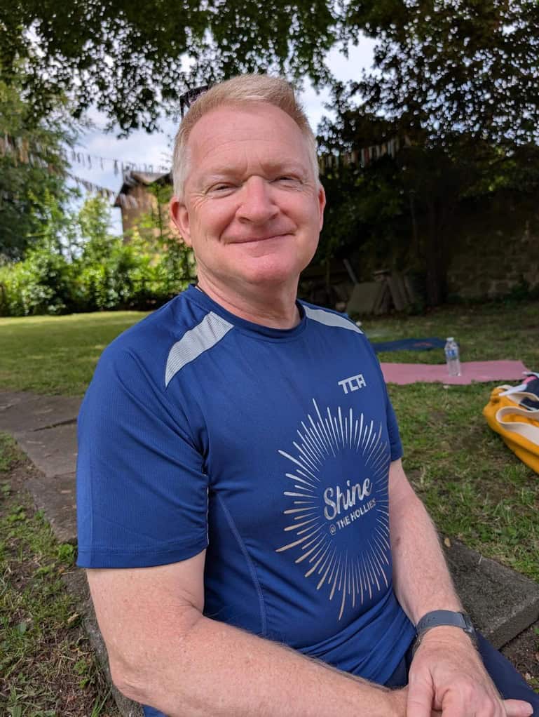 smiling man sitting outside in the garden, called Graham, yoga & Pilates teacher at Shine at The Hollies