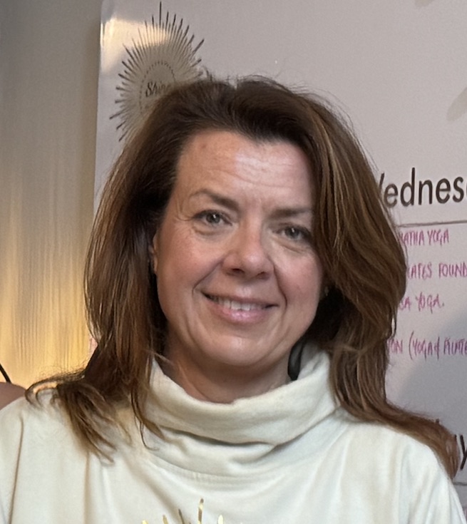 Lisa Langhorn, Co-Owner of Shine at the Hollies. 50 year old woman with brown hair, smiling, standing in the reception area