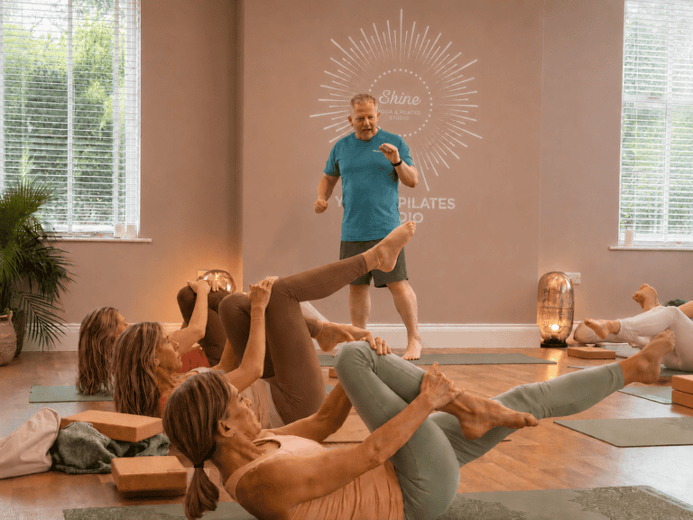 group of women practising mat pilates with a male pilates teacher instructing at shine at The Hollies