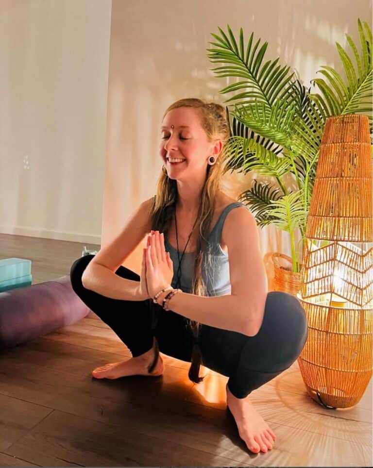 young smiling woman with long blond hair, called Jess, sitting in lotus position, yoga & Pilates teacher at Shine at The Hollies