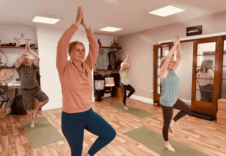 group of men and women practising hatha yoga standing in tree pose in a yoga class at Shine at The Hollies