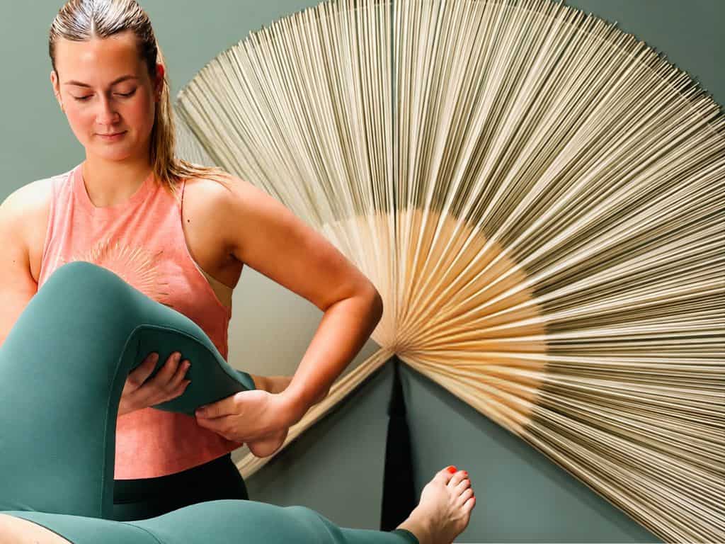 Lauren, Sports therapist at Shine Wellbeing doing hands-on treatment therapy on a client's leg