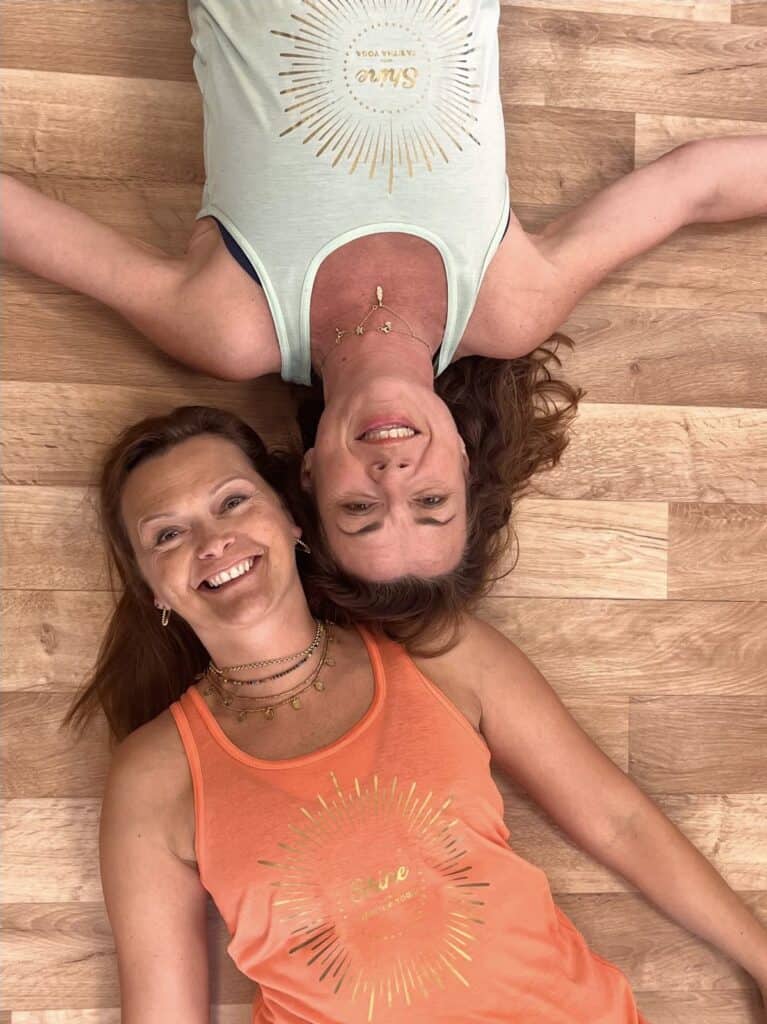 Tabitha and Lisa, owners of Shine at The Hollies Wellbeing Centre in Belper laying on the floor of the yoga studio head to head