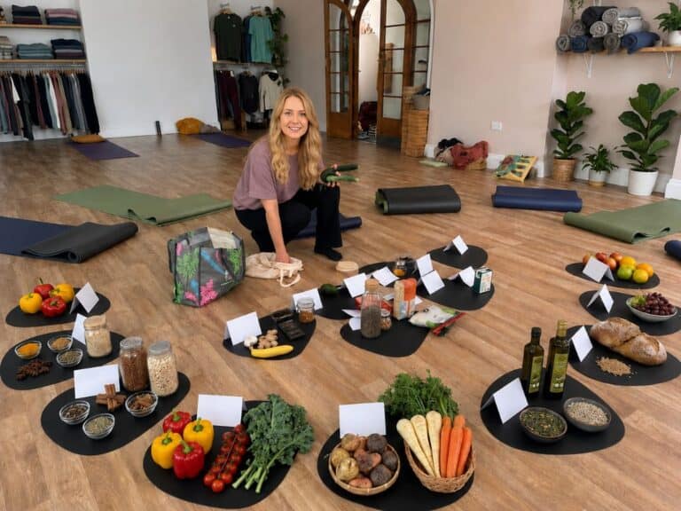 Female dietician kneeling on the floor in the Shine Yoga Studio surrounded by a range of healthy foods displayed as part of a healthy eating Workshop